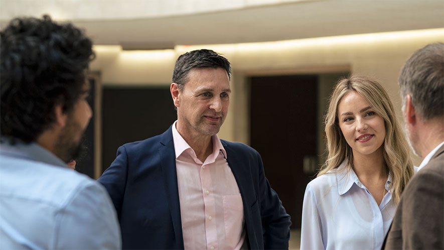 Group of four people engaged in conversation in a modern indoor setting.