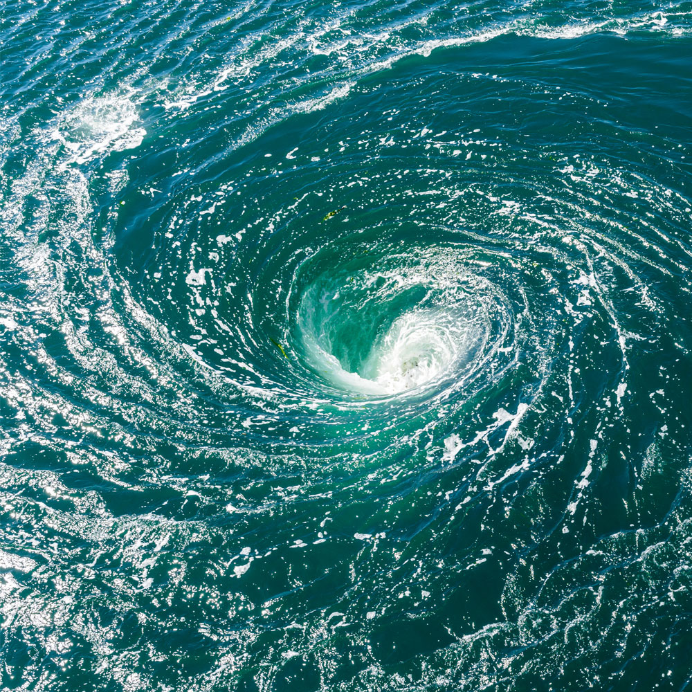 Whirlpool in dark blue water with foamy, swirling vortex in the center.