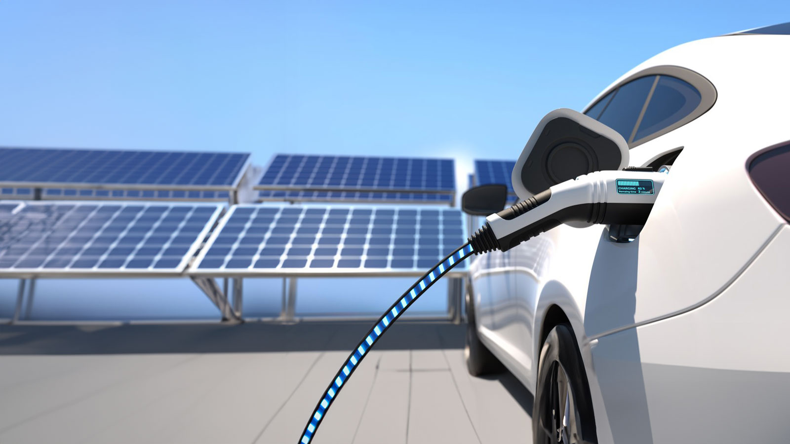 The image shows a white electric vehicle connected to a charging station. In the background, several large solar panels generate energy on a sunny day under a clear blue sky.
