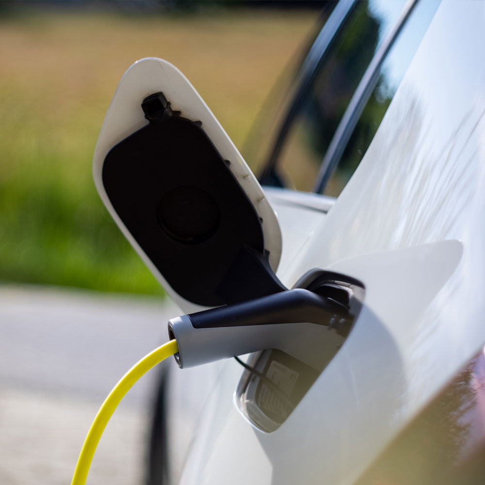 White electric car charging with yellow charging cable.