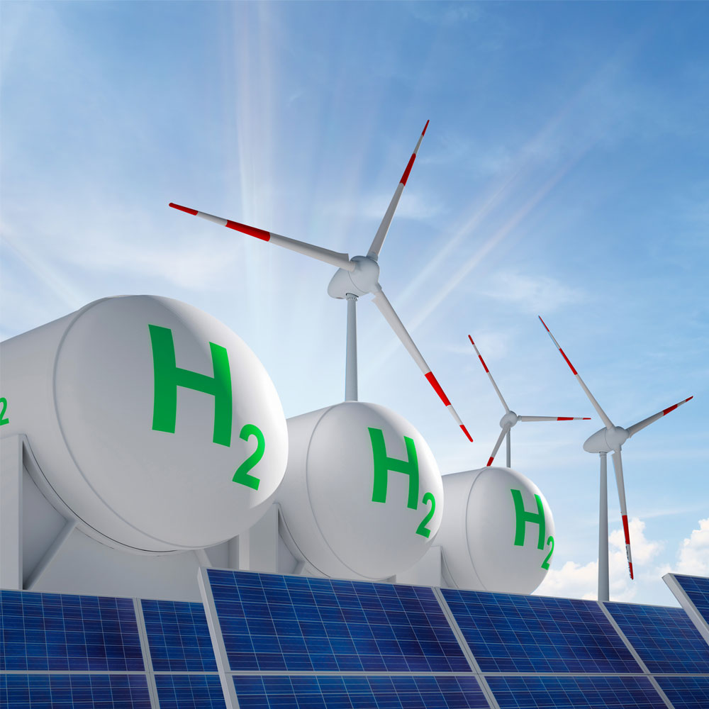 Wind turbines and large hydrogen storage tanks next to solar panels under a blue sky.
