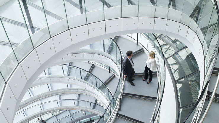 Two people talking on a spiral staircase in a business setting